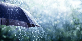 An umbrella outside with rain pouring down upon it.