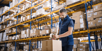 A male warehouse worker sealing cardboard boxes in a warehouse in Houston, Texas.